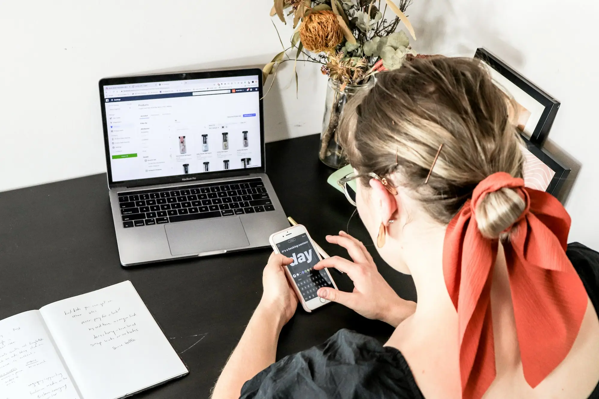 Accounts clerk checking bank details on her phone beside a laptop